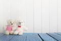 Couple of small white bear sitting on blue wooden table on white wooden wall