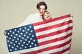 Couple on smiling faces holds flag of USA. Guy and girl happy with american flag, grey background. Travelling abroad Royalty Free Stock Photo