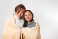 Couple smiling guy and girl in cozy sweaters hugged and covered with one warm plaid blanket Royalty Free Stock Photo