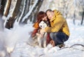 Couple smiling and having fun in winter park with their husky dog Royalty Free Stock Photo