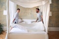 Couple smiling, laughing while making bed together in the morning in modern bedroom. couple, togetherness, morning, bedroom,