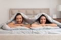 Couple smiling under covers, enjoying cozy morning Royalty Free Stock Photo