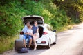 Couple with son having a coffee break while traveling in the countryside. A man and a woman are sitting in the trunk of Royalty Free Stock Photo