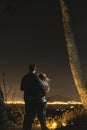 The couple stand on the background of the city lights. night time. Vertical photo. Naples. Volcano Vesuvio. Sea and romance. Royalty Free Stock Photo