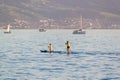 A couple stand up paddle boarding. A man and woman on a SUP Board on calm bay water