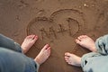 Couple standing on beach with heart and initials in sand