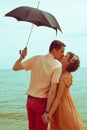 Couple standing on beach near water with umbrella Royalty Free Stock Photo