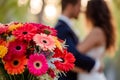 couple standing close, colorful bouquet of gerberas in the foreground