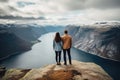 Couple standing on the edge of a cliff and looking at the fjord, rear view of Couple family traveling together on cliff edge in Royalty Free Stock Photo