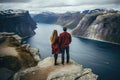 Couple standing on the edge of a cliff overlooking a fjord, rear view of Couple family traveling together on cliff edge in Norway Royalty Free Stock Photo