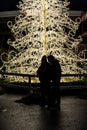 Couple standing in front of a light decorated christmas tree..