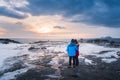 A couple standing on the frozen rock and ice beside the sea