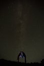 Couple is standing in mountains against night sky with milky way