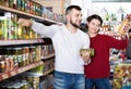Couple standing near shelves with canned goods at store Royalty Free Stock Photo