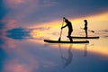 Couple standing on a paddle at sunset