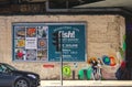 Couple standing on sidewalk in front of sign advertising fish at the Borough Market with art on the wall behind them Royalty Free Stock Photo