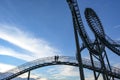 Couple standing on the stairs of the walkable roller coaster sculpture Tiger and Turtle against a blue sky with white clouds,