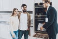 Couple stands with a salesman in a new kitchen. Royalty Free Stock Photo