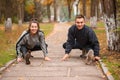 A couple stretches their leg muscles in a park in the fall. Royalty Free Stock Photo