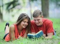 Couple of students lying on the grass in the Park and reading a book Royalty Free Stock Photo