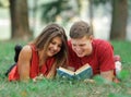 Couple of students lying on the grass in the Park and reading a book Royalty Free Stock Photo