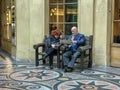 A couple studies Streetwise Paris while resting on a bench