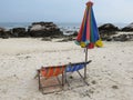 Couple of sun loungers and a folded beach tent stand on the shore of a deserted beach