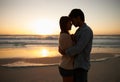 Couple, sunset and hugging on beach vacation, love and bonding on trip to ocean at dusk. People, embrace and romance on