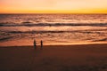 Couple at sunset runs along the sandy beach to the ocean and waves Royalty Free Stock Photo