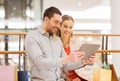 Couple with tablet pc and shopping bags in mall Royalty Free Stock Photo