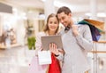 Couple with tablet pc and shopping bags in mall Royalty Free Stock Photo