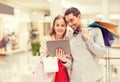 Couple with tablet pc and shopping bags in mall Royalty Free Stock Photo