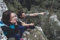 Couple taking a break while hiking, sitting at a viewpoint, pointing and looking at distance Royalty Free Stock Photo