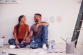 Couple Taking A Break From Painting Test Squares On Wall As They Decorate Room In New Home Together Royalty Free Stock Photo