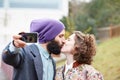 Couple taking a photograph of themselves kissing with a smartphone Royalty Free Stock Photo