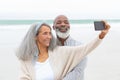 Couple taking a picture with smartphone at the beach Royalty Free Stock Photo