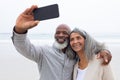 Couple taking a picture with smartphone at the beach Royalty Free Stock Photo
