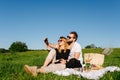 Couple taking selfie while having a picnic in a countryside on a green grass Royalty Free Stock Photo