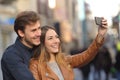 Couple taking selfie photo with a smart phone in the street