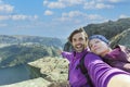 Couple taking a selfie on a rock and admiring a view on Preikestolen. Aerial shot, upper perspective on the couple. Endless view