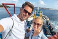 Casual couple taking selfie self portrait photo on ferry boat trip to their summer vacations island destination. Royalty Free Stock Photo