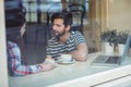 Couple talking while sitting by window at cafe