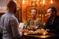 Couple talking to bartender behind bar counter in a cafe