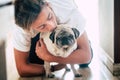 Couple of teenager and cute white pug - love and affection of two best frieds at home - loving the animals