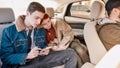 A couple of teenagers looking calm, using their smartphones while sitting together on back seat in the car Royalty Free Stock Photo