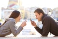 Couple of teens using their smart phones on vacation