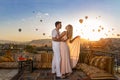 A couple and their romantic hugs in Cappadocia on the amazing background of hundred flying balloons