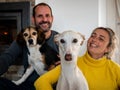 Couple with their two dogs, beagle, and greyhound next to the chimney in the house Royalty Free Stock Photo