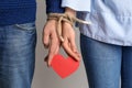 Couple with tied together hands holding paper heart on light background. Concept of addiction