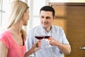 Couple toasting red wine glasses in kitchen Royalty Free Stock Photo